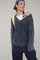 woman wearing a dark blue off-shoulder sweater with ribbed details and a casual cap