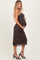woman wearing a black and brown leopard print maternity dress with pink straps, holding her baby bump