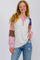 woman wearing a multicolored long sleeve henley top with buttons and a relaxed fit, paired with distressed blue jeans