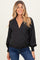 woman wearing a black polka dot maternity wrap top with long sleeves and a v-neckline