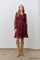 woman wearing a burgundy long sleeve lace dress with a smocked bodice and ruffled hem, paired with tan suede boots