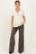 woman wearing a ribbed cream maternity top with buttons and dark brown flared maternity pants, showing her baby bump
