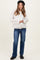 woman wearing a cream oversized button-up maternity jacket with wide sleeves and blue flared jeans