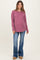 woman wearing a mauve ribbed long sleeve maternity top and blue flared jeans, showing a casual and stylish look