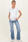 woman wearing a white short sleeve maternity top and blue flared jeans, showing her baby bump