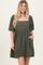woman wearing a dark green short puff sleeve dress with a square neckline and pockets