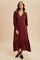woman wearing a burgundy long sleeve midi dress with a v-neckline and button details, styled with loafers