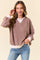 woman wearing a taupe oversized sweatshirt with white banded cuffs and hem, styled with light blue jeans