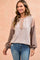 woman wearing a light beige and taupe color block long sleeve top with buttons, styled with blue jeans