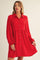 woman wearing a bright red long sleeve button-up dress with a fitted waist and flared skirt