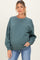 woman wearing a green oversized maternity sweatshirt and showing her baby bump with light blue jeans