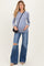 woman wearing a light blue long sleeve maternity top and distressed flared jeans, showcasing her baby bump