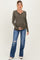 woman wearing a dark olive green long sleeve maternity henley top and holding her baby bump with distressed blue jeans