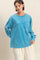 woman wearing an oversized blue long sleeve t-shirt with a front pocket and relaxed fit