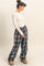 woman wearing a white long sleeve ribbed top and plaid wide-leg pants with side pockets