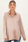 woman wearing a beige maternity shirt with a button front and long sleeves, showing a baby bump