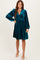 woman wearing a teal velvet long sleeve dress with a v-neck and a flared skirt