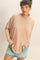 woman wearing a beige long sleeve turtleneck top with an oversized fit and front pockets, paired with a denim mini skirt
