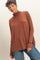 woman wearing a rust-colored turtleneck long sleeve top with relaxed fit and dropped shoulders