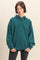 woman wearing a dark teal oversized polo sweatshirt with a collared neckline and long sleeves