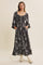 woman wearing a black floral maxi dress with puff sleeves and pockets, posed with hands in pockets