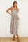 woman wearing a floral maxi dress with tie straps and a smocked bodice, posing with one hand in a pocket