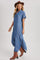 woman wearing a blue denim button-up maxi dress and a brown hat, paired with brown knee-high boots