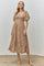 woman wearing a beige lace midi dress with puff sleeves and a cinched waist, standing on a concrete floor
