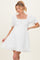 woman wearing a white short puff sleeve maternity dress with a square neckline and frill hem