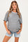 woman wearing a striped maternity top in blue and mustard with blue shorts and a visible baby bump