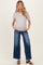 woman wearing a light gray maternity short sleeve top and wide-leg blue jeans, with a visible baby bump