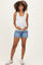 woman wearing a white ribbed maternity tank top and denim shorts, holding her baby bump