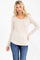 woman wearing a light beige long sleeve henley top with button details and a rounded hem, paired with blue jeans