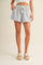 woman wearing light blue linen shorts with an elastic waistband and drawstring, styled with platform sandals