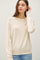 woman wearing a beige long sleeve sweater with a relaxed fit and round neckline, paired with light blue jeans