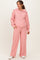 woman wearing a light pink maternity tracksuit with a zip-up hoodie and wide-leg pants, holding a baby bump
