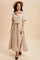 woman wearing a beige striped button-up maxi dress with a tie waist and short sleeves, paired with a hat and flats