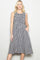 woman wearing a black and white gingham print sleeveless dress with a smocked bodice and pockets