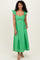 woman wearing a green midi dress with ruffled straps and a cutout detail at the waist, styled with open-toed sandals