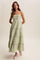 woman wearing a light green tiered maxi dress with floral embroidery and thin straps, paired with pink flats