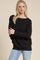 woman wearing a black oversized sweater with a wide neckline and relaxed fit, paired with light blue jeans