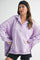woman wearing a lavender oversized pullover sweatshirt with a collar and side slits, paired with black bike shorts