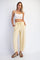 woman wearing a white crop top and yellow drawstring pants, posing with hands in pockets