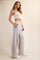 woman wearing a light grey crop top and matching wide-leg sweatpants with side pockets