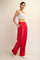 woman wearing a white crop top and red wide-leg sweatpants with side pockets and white piping details