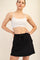 woman wearing a white cropped sports bra and a black drawstring skirt