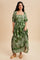 woman wearing a green maxi dress with white floral print and puff sleeves, standing against a neutral background