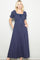 woman wearing a navy blue maxi dress with puff sleeves and a smocked bodice, featuring a drawstring and pockets