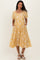 woman wearing a yellow maternity dress with puff sleeves and white floral embroidery, featuring pockets and a tiered skirt