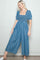 woman wearing a denim blue smocked square neck jumpsuit with puff sleeves and wide legs